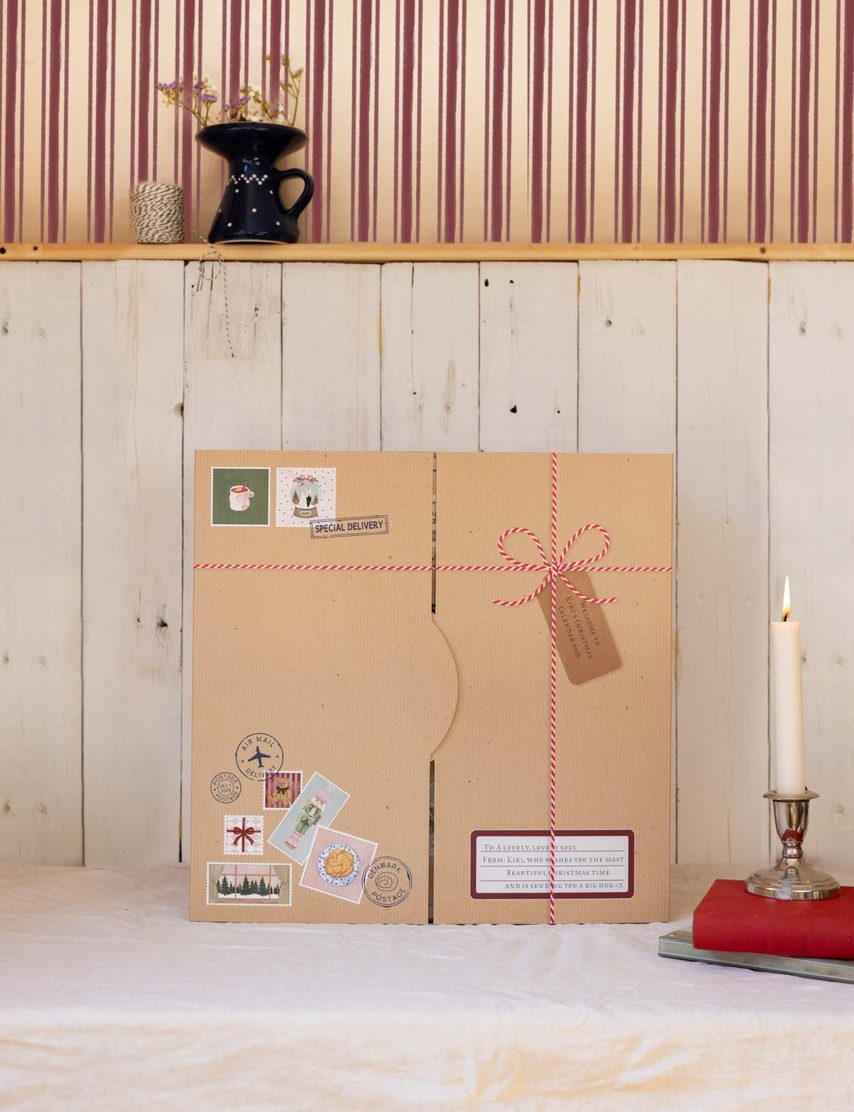 Kiki Adventskalender 2026, verpackt mit Kerze und Briefmarken